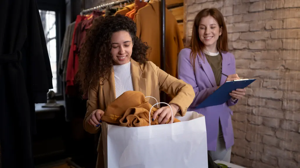 Duas mulheres organizando sacolas de roupas, uma delas usando prancheta com o Sistema CRIAR Varejo.